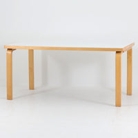 Alvar AaltoがデザインしArtek社より製造されたこちらのダイニングテーブルは、フィンランドモダニズムを象徴する一本。バーチ材の脚部に柔らかくカーブを描くLレッグ構造が取り入れられ、軽やかでありながらも高い強度を実現しています。天板は実用性に優れたホワイトラミネート仕上げで、幅150cmのゆとりあるサイズは家族での食卓やワークスペースにも最適です。幕板の一部に交換がありますが、アアルト製品が多く採用されていたデンマークの公共施設で丁寧に使用されていた個体です。