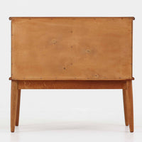 デンマーク製の小ぶりなキャビネットです。チーク材をメインに、オーク材やビーチ材を組み合わせることで、温かみのある色調と軽快な雰囲気を併せ持っています。左側は扉付き収納、右側には3杯の引き出しを備え、実用性とデザイン性を両立。丸みを帯びた取っ手や脚部のテーパーラインが北欧家具らしい柔らかな印象を与えます。幅63cmとコンパクトなサイズで、リビングや寝室、玄関など限られたスペースでも活躍する、ビンテージならではの風合いを持つ一台です。