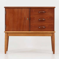 デンマーク製の小ぶりなキャビネットです。チーク材をメインに、オーク材やビーチ材を組み合わせることで、温かみのある色調と軽快な雰囲気を併せ持っています。左側は扉付き収納、右側には3杯の引き出しを備え、実用性とデザイン性を両立。丸みを帯びた取っ手や脚部のテーパーラインが北欧家具らしい柔らかな印象を与えます。幅63cmとコンパクトなサイズで、リビングや寝室、玄関など限られたスペースでも活躍する、ビンテージならではの風合いを持つ一台です。