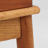 デンマーク製の小ぶりなキャビネットです。チーク材をメインに、オーク材やビーチ材を組み合わせることで、温かみのある色調と軽快な雰囲気を併せ持っています。左側は扉付き収納、右側には3杯の引き出しを備え、実用性とデザイン性を両立。丸みを帯びた取っ手や脚部のテーパーラインが北欧家具らしい柔らかな印象を与えます。幅63cmとコンパクトなサイズで、リビングや寝室、玄関など限られたスペースでも活躍する、ビンテージならではの風合いを持つ一台です。