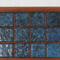 チーク材の温かみある木肌に、落ち着いたブルー系陶磁器タイルをあしらったネストテーブルは、北欧ビンテージらしい実用性と装飾性を兼ね備えたセットです。大小3台を重ねて収納できる合理的な構造で、必要に応じてサイドテーブルや補助台として柔軟に使い分けが可能。角を丸く仕上げた天板や細身の脚部には丁寧な木工技術が感じられ、経年により深みを増した表情が空間に静かな存在感を添えます。