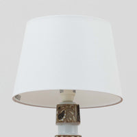 Nils Thorssonがデザインし、Royal Copenhagen社から発表された「BACA」シリーズのテーブルランプは、高さ39cmのバランスの取れたサイズ感で、北欧ビンテージらしい存在感を放ちます。陶磁器製のベースには細やかな装飾模様が施され、グラフィカルでありながら落ち着いた色調が空間に洗練された雰囲気を添えます。リネンシェードを透過する柔らかな光が温もりを演出し、リビングやベッドサイドに最適です。年月を経て深みを増した質感と工芸的な美しさを楽しめる一点物です。