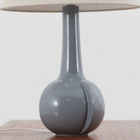 Royal Copenhagen社製のテーブルランプ「1013-3807」です。高さ50cmと存在感のある大きめサイズで、陶磁器ならではの艶やかな質感のベースにリネンシェードが組み合わされ、落ち着いた雰囲気を醸し出しています。クラシカルなフォルムに北欧らしい洗練されたデザインが融合し、点灯時には柔らかく温かな光が空間を包み込みます。リビングやベッドサイドのアクセントとしてはもちろん、インテリアオブジェとしても映える北欧ビンテージの逸品です。