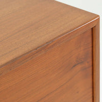 デンマーク製の北欧ビンテージサイドチェストです。チーク材の落ち着いた色合いと美しい木目が際立ち、奥行きをしっかりと確保した設計が実用性を高めています。上部はオープンスペースと、下段には小ぶりな引き出しを配置。真鍮調のつまみがさりげないアクセントとなり、直線的なフォルムとすらりとした脚部が軽やかな印象を与えます。ベッドサイドやリビングでの小物収納、簡易デスクとしても活躍し、経年による艶やかな風合いが空間に温もりを添える一台です。