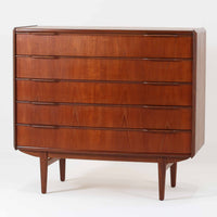 北欧ビンテージらしい端正な佇まいが魅力の5段チェストです。良質な木材を用いた本体は、横に流れる美しい木目に加え、角だけでなく前板を含む本体全体が緩やかな曲線を描く、有機的で上質なフォルムが特徴です。引き出し前板には手掛け一体型の彫り込みが施され、丸みを帯びた造形と相まって柔らかな印象を与えます。高い工作精度が感じられるクオリティの高い一台で、収納力に優れたサイズながら脚付き構造により軽やかさも備え、寝室やリビングの主収納として活躍します。Vordingborg Mobelfabrik社製と伝えられていますが確証はなく、メーカー不詳のビンテージ品としてご紹介します。経年変化によって深みを増した木肌が、空間に上質な存在感をもたらします。