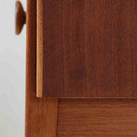 デンマークのサイドチェストです。アフロモシア材の落ち着いた色味の本体に、ビーチ材で成形された横溝装飾の引き出し前板がアクセントとなり、シンプルな構造の中にリズム感のある表情を生み出しています。幅54cmのコンパクトなサイズで、ベッドサイドやソファ脇、玄関先などにも取り入れやすく、引き出し付きで実用性も十分です。経年により深まった木肌の風合いと丁寧なつくりが、北欧ビンテージらしい静かな存在感を空間に添えてくれます。