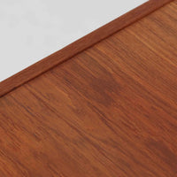 こちらの小ぶりなボードは、温かみのあるチーク材を用いたすっきりとした佇まいが魅力の北欧ビンテージ家具で、スライド扉を開くと左右に棚板付きの収納スペースが現れ、日用品や小物を効率よく整理できます。直線的な箱型の構造に、細身でテーパーの効いた脚部が軽やかな印象を添え、コンパクトながら存在感のある設計が空間に落ち着いたアクセントをもたらします。経年で深まった木肌の質感も味わい深く、リビングや玄関脇のサイド収納としても取り入れやすい一台です。