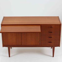 スウェーデン製のディスプレイシェルフです。チーク材の温かみある木目が美しく、上段にはオープンシェルフと小引き出し、下段には引き棚と引き戸収納と4段の引き出しが備わった実用性の高いデザインです。下段収納部には奥行きの浅い棚板が設けられており、収納する物に応じて使い分けができます。食器や本、雑貨などをすっきりと整理しながら、見せる収納としても楽しめます。扉の錠前は故障しているため施錠・開錠はできませんが、本鍵を取手として使用できるようにしています。また、扉をしっかり固定するためローラーキャッチを新たに取り付け済みです。引き出しはスムーズに開閉でき、細部まで丁寧に仕上げられています。細身のテーパー脚が全体を軽やかに見せ、経年で深みを増したチークの風合いが空間に上質な落ち着きをもたらす、北欧らしい一台です。