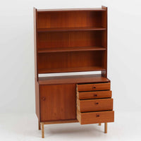 チーク材とオーク材を組み合わせて作られたスウェーデン製のディスプレイシェルフです。幅90cmと使いやすいサイズ感で、上部の棚には本やオブジェを、下部の引き戸と引き出しには日用品を収納できる実用性の高い構成となっています。滑らかな木肌や丁寧な造りには職人技が感じられ、経年により深みを増した木の風合いが空間に温かみをもたらします。リビングやダイニングはもちろん、書斎や寝室の収納兼ディスプレイとしても活躍する、北欧ビンテージ家具らしいシンプルかつ機能的な一台です。