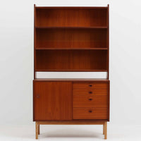 チーク材とオーク材を組み合わせて作られたスウェーデン製のディスプレイシェルフです。幅90cmと使いやすいサイズ感で、上部の棚には本やオブジェを、下部の引き戸と引き出しには日用品を収納できる実用性の高い構成となっています。滑らかな木肌や丁寧な造りには職人技が感じられ、経年により深みを増した木の風合いが空間に温かみをもたらします。リビングやダイニングはもちろん、書斎や寝室の収納兼ディスプレイとしても活躍する、北欧ビンテージ家具らしいシンプルかつ機能的な一台です。