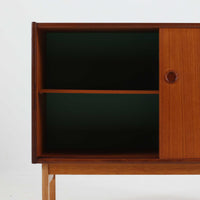 スウェーデン製のチーク材とオーク材を組み合わせたディスプレイシェルフです。幅90cmと程よいサイズ感で、上部の棚は書籍やオブジェの展示に適し、下部の引き戸収納は日用品や小物をすっきりと収めることができます。丸みを帯びた取っ手が温かみのあるアクセントとなり、北欧家具らしいシンプルで実用的なデザインを際立たせています。経年によって深みを増したチークの木目とオークのコントラストが上品な存在感を放ち、リビングや書斎の空間に落ち着いた雰囲気を添えるビンテージ家具です。