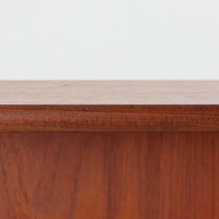 スウェーデン製のチーク材とオーク材を組み合わせたディスプレイシェルフです。幅90cmと程よいサイズ感で、上部の棚は書籍やオブジェの展示に適し、下部の引き戸収納は日用品や小物をすっきりと収めることができます。丸みを帯びた取っ手が温かみのあるアクセントとなり、北欧家具らしいシンプルで実用的なデザインを際立たせています。経年によって深みを増したチークの木目とオークのコントラストが上品な存在感を放ち、リビングや書斎の空間に落ち着いた雰囲気を添えるビンテージ家具です。