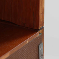 スウェーデン製のディスプレイシェルフです。上段には3段のオープンシェルフが設けられ、本や雑貨、オブジェなどを美しくディスプレイできます。下段にはスライド扉収納が備わり、内部の棚板によって整理しやすく、見せたくない収納にも便利です。チーク材の温もりある木目と、丸い掘り込み取っ手の柔らかなデザインが印象的で、北欧家具らしい穏やかな雰囲気を演出します。背面のグリーンの化粧板が空間に個性を添え、飾るアイテムをより際立たせます。本体にはチーク材、脚部にはオーク材が使用されており、素材のコントラストも魅力のひとつです。下段収納部の棚板にわずかな反りがありますが、裏返して使用することで目立たなくなります。軽やかな佇まいと実用性を兼ね備えた、北欧ビンテージらしい一台です。