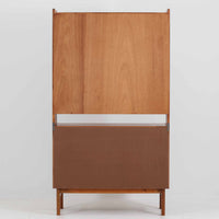 スウェーデン製のディスプレイシェルフです。上段には3段のオープンシェルフが設けられ、本や雑貨、オブジェなどを美しくディスプレイできます。下段にはスライド扉収納が備わり、内部の棚板によって整理しやすく、見せたくない収納にも便利です。チーク材の温もりある木目と、丸い掘り込み取っ手の柔らかなデザインが印象的で、北欧家具らしい穏やかな雰囲気を演出します。背面のグリーンの化粧板が空間に個性を添え、飾るアイテムをより際立たせます。本体にはチーク材、脚部にはオーク材が使用されており、素材のコントラストも魅力のひとつです。下段収納部の棚板にわずかな反りがありますが、裏返して使用することで目立たなくなります。軽やかな佇まいと実用性を兼ね備えた、北欧ビンテージらしい一台です。