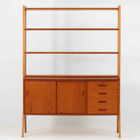 スウェーデン製のディスプレイシェルフで、チーク材とビーチ材の組み合わせが生み出す温かみと軽やかなコントラストが魅力です。上部はオープンな3段棚で開放感があり、お気に入りの雑貨や書籍をすっきりと美しく飾ることができます。下部には引き戸収納と4杯の引き出しを備え、日用品や小物を整理するのにも便利です。幅120cmと取り入れやすいサイズ感で、リビングやダイニングを軽やかに演出。経年による木肌の深みが加わり、シンプルながらも存在感を放つビンテージらしい一台です。