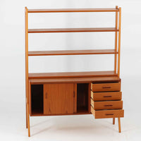 スウェーデン製のディスプレイシェルフで、チーク材とビーチ材の組み合わせが生み出す温かみと軽やかなコントラストが魅力です。上部はオープンな3段棚で開放感があり、お気に入りの雑貨や書籍をすっきりと美しく飾ることができます。下部には引き戸収納と4杯の引き出しを備え、日用品や小物を整理するのにも便利です。幅120cmと取り入れやすいサイズ感で、リビングやダイニングを軽やかに演出。経年による木肌の深みが加わり、シンプルながらも存在感を放つビンテージらしい一台です。