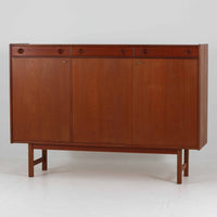 Tage Olofsson(ターゲ・オロフソン)によるデザインで、Ulferts Mobler社製のキッチンキャビネットです。チーク材を贅沢に使用した美しい木目と、丸型の引き手がアクセントとなったデザインが特徴です。上部にはカトラリーなどを整理できる仕切り付きの引き出しが3杯、下部には棚板付きの扉収納が備えられており、食器やキッチン用品を効率的に収納できます。北欧家具らしい温もりと機能性を兼ね備えた一台で、リビングやダイニングにも自然に溶け込む上品な佇まいです。