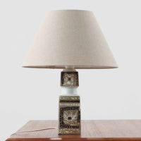 Nils Thorssonがデザインし、Royal Copenhagen社から発表された「BACA」シリーズのテーブルランプは、高さ38cmのバランスの取れたサイズ感で、北欧ビンテージらしい存在感を放ちます。陶磁器製のベースには細やかな装飾模様が施され、グラフィカルでありながら落ち着いた色調が空間に洗練された雰囲気を添えます。リネンシェードを透過する柔らかな光が温もりを演出し、リビングやベッドサイドに最適です。年月を経て深みを増した質感と工芸的な美しさを楽しめる一点物です。