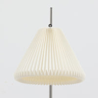 Michael Bang(マイケル・バン)によるデザインで、Le Klint(レ・クリント)から発表されたフロアランプModel 321です。高さ131cmのスチール製フレームは、無駄のない直線的なフォルムと精巧なディテールが際立ち、モダンな空間に調和します。特徴的なスライド機構によりランプの高さを調整でき、読書灯から間接照明まで幅広い用途に対応。ハンドクラフトによるプリーツシェードは柔らかい光を生み出し、北欧ビンテージならではの温もりと機能美を感じさせます。