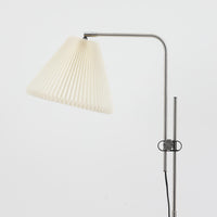 Michael Bang(マイケル・バン)によるデザインで、Le Klint(レ・クリント)から発表されたフロアランプModel 321です。高さ131cmのスチール製フレームは、無駄のない直線的なフォルムと精巧なディテールが際立ち、モダンな空間に調和します。特徴的なスライド機構によりランプの高さを調整でき、読書灯から間接照明まで幅広い用途に対応。ハンドクラフトによるプリーツシェードは柔らかい光を生み出し、北欧ビンテージならではの温もりと機能美を感じさせます。