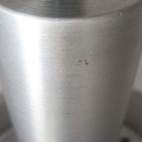 Carl Thoreがデザインし、Granhaga社より発表された直径28cmのペンダントライトです。アルミ製のシェードを幾重にも重ねた構造が特徴で、点灯すると隙間から柔らかな光が漏れ、独特の陰影と奥行きを生み出します。外側はシルバー、内側には紫がかった色味が施され、消灯時と点灯時で異なる表情を楽しめます。モダンでありながら温かみのある北欧らしい光のデザインは、ダイニングやリビングの照明として空間にアクセントを与えます。ビンテージならではの存在感を放つ希少な一品です。