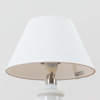 Sidse Werner(シセ・ヴェルナー)がデザインし、Holmegaard(ホルムガード)より製造されたテーブルランプ「Apoteker」です。高さ29cmと小ぶりなサイズで、艶やかなホワイトガラスのベースが柔らかな印象を与えます。リネンシェードを通した光は優しく拡散し、ナチュラルな雰囲気を演出。シンプルでありながら彫刻的なフォルムが存在感を放ち、ベッドサイドやデスク、リビングのサイドテーブルなど様々な空間で活躍します。北欧デザインの温もりを感じられるビンテージ照明です。