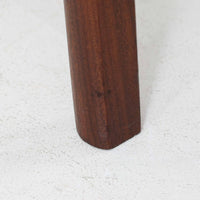 チーク材を用いた小ぶりなキャビネットは、直線を基調としつつ柔らかな丸みを持たせた側板と脚部のラインが印象的な北欧ビンテージ家具です。前板一枚で構成されたフラップ扉には掘り込み式の取っ手が設けられ、開閉時の所作も美しく、内部には実用的な収納棚を備えています。幅69cmと取り入れやすいサイズ感で、リビングや玄関、ベッドサイドの収納としても活躍し、経年により深みを増したチーク材の木目と職人技が静かな存在感を放つ一台です。