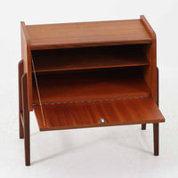 チーク材を用いた小ぶりなキャビネットは、直線を基調としつつ柔らかな丸みを持たせた側板と脚部のラインが印象的な北欧ビンテージ家具です。前板一枚で構成されたフラップ扉には掘り込み式の取っ手が設けられ、開閉時の所作も美しく、内部には実用的な収納棚を備えています。幅69cmと取り入れやすいサイズ感で、リビングや玄関、ベッドサイドの収納としても活躍し、経年により深みを増したチーク材の木目と職人技が静かな存在感を放つ一台です。