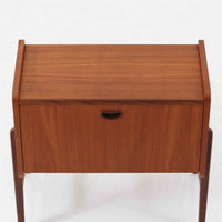 チーク材を用いた小ぶりなキャビネットは、直線を基調としつつ柔らかな丸みを持たせた側板と脚部のラインが印象的な北欧ビンテージ家具です。前板一枚で構成されたフラップ扉には掘り込み式の取っ手が設けられ、開閉時の所作も美しく、内部には実用的な収納棚を備えています。幅69cmと取り入れやすいサイズ感で、リビングや玄関、ベッドサイドの収納としても活躍し、経年により深みを増したチーク材の木目と職人技が静かな存在感を放つ一台です。