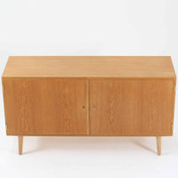 Poul Hundevadが手がけ、Hundevad & Coより製作されたキャビネットです。オーク材の端正な木目を活かしたフラットな扉構成と、細身のテーパードレッグが北欧モダンらしい軽やかさを演出します。内部は可動棚と可動式の浅型トレイを備え、書類や食器、小物まで用途に応じた整理が可能。天板下の構造や金物の収まりにも丁寧な作りが感じられ、長年の使用で深みを増した素材感がビンテージならではの魅力として空間に静かな存在感を添えます。