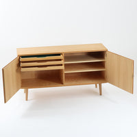 Poul Hundevadが手がけ、Hundevad & Coより製作されたキャビネットです。オーク材の端正な木目を活かしたフラットな扉構成と、細身のテーパードレッグが北欧モダンらしい軽やかさを演出します。内部は可動棚と可動式の浅型トレイを備え、書類や食器、小物まで用途に応じた整理が可能。天板下の構造や金物の収まりにも丁寧な作りが感じられ、長年の使用で深みを増した素材感がビンテージならではの魅力として空間に静かな存在感を添えます。