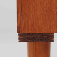 デンマーク製のこちらのローボードは、温かみあるチーク材を用いた端正な佇まいが魅力で、枠組みに厚みをもたせたスライド扉や細身のテーパー脚など、北欧ビンテージらしい上質な意匠が随所に感じられる一台です。内部は左右で棚構成が異なり、日用品から書類、メディア類まで整理しやすく、テレビボードやサイドキャビネットとしても活躍します。経年により深みを増した木肌の美しさと、シンプルながら丁寧に仕上げられた職人技が空間に落ち着きと温もりを添えるビンテージ家具です。