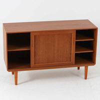 デンマーク製のこちらのローボードは、温かみあるチーク材を用いた端正な佇まいが魅力で、枠組みに厚みをもたせたスライド扉や細身のテーパー脚など、北欧ビンテージらしい上質な意匠が随所に感じられる一台です。内部は左右で棚構成が異なり、日用品から書類、メディア類まで整理しやすく、テレビボードやサイドキャビネットとしても活躍します。経年により深みを増した木肌の美しさと、シンプルながら丁寧に仕上げられた職人技が空間に落ち着きと温もりを添えるビンテージ家具です。