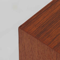 デンマーク製のこちらのローボードは、温かみあるチーク材を用いた端正な佇まいが魅力で、枠組みに厚みをもたせたスライド扉や細身のテーパー脚など、北欧ビンテージらしい上質な意匠が随所に感じられる一台です。内部は左右で棚構成が異なり、日用品から書類、メディア類まで整理しやすく、テレビボードやサイドキャビネットとしても活躍します。経年により深みを増した木肌の美しさと、シンプルながら丁寧に仕上げられた職人技が空間に落ち着きと温もりを添えるビンテージ家具です。