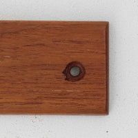 チーク材の温かみあるベースにメタル製の3連フックを組み合わせたデンマーク製のウォールハンガーです。丸みのある木製キャップ付きのフックはコートやバッグを掛けても傷つきにくく、機能性とデザイン性を両立した北欧ビンテージらしいディテールが魅力です。玄関や寝室、ワークスペースなど壁面を活用した収納に便利で、単体での使用はもちろん複数並べて使用しても美しく空間に溶け込みます。ミニマルなデザインでインテリアを選ばず永くお使いいただけるアイテムです。