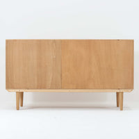 Poul Hundevadがデザインし、Hundevad & Coより製作された蛇腹仕様のサイドボードです。オーク材の穏やかで上品な木目を活かした外観に、横方向へ滑らかに開閉する蛇腹扉を組み合わせた、機能美あふれる一台。扉の開閉時に前後のスペースを取らない構造は、動線を妨げず実用性にも優れています。内部は棚板構成で収納力が高く、食器や書類、リビング周りの小物まで幅広く対応。細身の脚部が全体を軽やかに引き締め、経年によって深みを増した素材感が北欧ビンテージならではの静かな存在感を空間にもたらします。