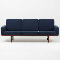 こちらは、ウェグナーデザインの人気モデル、GE236の3人掛けソファです。後ろ姿が非常に美しいため、あえて壁に寄せず背面を見せる配置もおすすめです。クッション内部にはスプリングが内蔵されており、座り心地も良好です。さらに、こちらは現地でも希少なアフロモシア材(通称アフリカンチーク)が使用された特別なモデルです。GE236のチーク材仕様として一般的に認識されているのは、このアフロモシア材が使用されたモデルを指します。GETAMA社の刻印も確認できます。