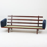 こちらは、ウェグナーデザインの人気モデル、GE236の3人掛けソファです。後ろ姿が非常に美しいため、あえて壁に寄せず背面を見せる配置もおすすめです。クッション内部にはスプリングが内蔵されており、座り心地も良好です。さらに、こちらは現地でも希少なアフロモシア材(通称アフリカンチーク)が使用された特別なモデルです。GE236のチーク材仕様として一般的に認識されているのは、このアフロモシア材が使用されたモデルを指します。GETAMA社の刻印も確認できます。