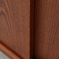 デンマーク製ローボードです。チーク材ならではの赤みを帯びた美しい木目が前面にあらわれ、引き戸には掘り込み式の丸い取っ手を配したミニマルな意匠が北欧らしい静かな存在感を放ちます。幅80cmの小ぶりなサイズ感で、リビングのテレビ台としてはもちろん、書斎やベッドルームでの収納家具としても取り入れやすく、内部には棚板を備え実用性も十分です。経年によって深みを増した木肌の表情と丁寧なつくりが、ビンテージならではの温もりを空間に添えてくれる一台です。