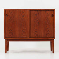 デンマーク製ローボードです。チーク材ならではの赤みを帯びた美しい木目が前面にあらわれ、引き戸には掘り込み式の丸い取っ手を配したミニマルな意匠が北欧らしい静かな存在感を放ちます。幅80cmの小ぶりなサイズ感で、リビングのテレビ台としてはもちろん、書斎やベッドルームでの収納家具としても取り入れやすく、内部には棚板を備え実用性も十分です。経年によって深みを増した木肌の表情と丁寧なつくりが、ビンテージならではの温もりを空間に添えてくれる一台です。