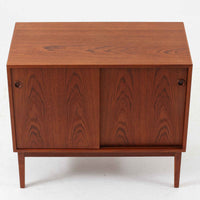 デンマーク製ローボードです。チーク材ならではの赤みを帯びた美しい木目が前面にあらわれ、引き戸には掘り込み式の丸い取っ手を配したミニマルな意匠が北欧らしい静かな存在感を放ちます。幅80cmの小ぶりなサイズ感で、リビングのテレビ台としてはもちろん、書斎やベッドルームでの収納家具としても取り入れやすく、内部には棚板を備え実用性も十分です。経年によって深みを増した木肌の表情と丁寧なつくりが、ビンテージならではの温もりを空間に添えてくれる一台です。