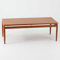 Grete Jalk(グレーテ・ヤルク)によるデザイン、France & Son社製のセンターテーブル Model 622/54です。繊細なテーパードレッグに天板と幕板の隙間を持たせた軽やかな構造が美しく、真鍮パーツがアクセントとして上質な存在感を添えています。幅150cmのゆったりとしたサイズはリビングでの使用に最適で、ソファ前のテーブルとしてはもちろん展示台としてもバランスよく馴染みます。北欧モダンを象徴する端正なラインとチーク材の豊かな木目が魅力で、ロゴプレートの仕様より1960年代半ば〜1969年頃に製造された個体と推測され、ミッドセンチュリー期を代表する名作ビンテージ家具です。