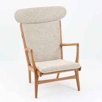 Hans J. Wegnerがデザインし、AP Stolenが製作したAP15ハイバックシングルソファです。オーク材の滑らかな木肌を活かしたフレームに、包み込むような背とヘッドレストを備えた優美なフォルムが印象的。彫刻的なアーム形状や前後に傾斜した脚部など、随所にウェグナーらしい造形美が感じられます。ホワイト系の色味が空間を明るく上品な印象に整えます。ゆったりと身体を預けられる快適な座り心地と、経年で深みを増した木部の風合いが格調ある雰囲気をもたらす北欧ビンテージの名品です。