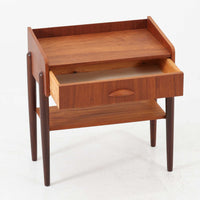 デンマーク製のサイドチェストです。チーク材ならではの温かみある木目と落ち着いた色合いが美しく、側板を立ち上げた天板形状がさりげないデザインアクセントになっています。引き出しには手掛けとして一体成形された取っ手があしらわれ、滑らかな開閉とすっきりとした正面意匠を両立しています。幅52cmの扱いやすいサイズ感で、ベッドサイドやソファ脇、玄関先などにも取り入れやすく、下段の棚板は本や小物の収納にも便利です。経年変化によって深みを増したチークの表情が、ビンテージならではの落ち着いた存在感を空間にもたらします。