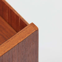 デンマーク製のサイドチェストです。チーク材ならではの温かみある木目と落ち着いた色合いが美しく、側板を立ち上げた天板形状がさりげないデザインアクセントになっています。引き出しには手掛けとして一体成形された取っ手があしらわれ、滑らかな開閉とすっきりとした正面意匠を両立しています。幅52cmの扱いやすいサイズ感で、ベッドサイドやソファ脇、玄関先などにも取り入れやすく、下段の棚板は本や小物の収納にも便利です。経年変化によって深みを増したチークの表情が、ビンテージならではの落ち着いた存在感を空間にもたらします。