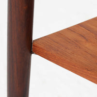 デンマーク製のサイドチェストです。チーク材ならではの温かみある木目と落ち着いた色合いが美しく、側板を立ち上げた天板形状がさりげないデザインアクセントになっています。引き出しには手掛けとして一体成形された取っ手があしらわれ、滑らかな開閉とすっきりとした正面意匠を両立しています。幅52cmの扱いやすいサイズ感で、ベッドサイドやソファ脇、玄関先などにも取り入れやすく、下段の棚板は本や小物の収納にも便利です。経年変化によって深みを増したチークの表情が、ビンテージならではの落ち着いた存在感を空間にもたらします。