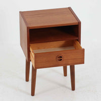 デンマーク製のサイドチェストで、温かみのあるチーク材を用いた北欧ビンテージらしい佇まいが魅力です。上段のオープンスペースは読みかけの本や小物の収納に便利で、下段の引き出しにはアイコン的な丸型取手があしらわれ、シンプルな中にも愛嬌のあるアクセントを添えています。細く伸びたテーパードレッグが軽やかな印象を与え、ベッドサイドやソファ横のサイドテーブルとしても活躍。経年変化による深い色艶が空間に上質な雰囲気をもたらすビンテージ家具です。