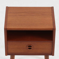 デンマーク製のサイドチェストで、温かみのあるチーク材を用いた北欧ビンテージらしい佇まいが魅力です。上段のオープンスペースは読みかけの本や小物の収納に便利で、下段の引き出しにはアイコン的な丸型取手があしらわれ、シンプルな中にも愛嬌のあるアクセントを添えています。細く伸びたテーパードレッグが軽やかな印象を与え、ベッドサイドやソファ横のサイドテーブルとしても活躍。経年変化による深い色艶が空間に上質な雰囲気をもたらすビンテージ家具です。