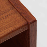 デンマーク製のサイドチェストで、温かみのあるチーク材を用いた北欧ビンテージらしい佇まいが魅力です。上段のオープンスペースは読みかけの本や小物の収納に便利で、下段の引き出しにはアイコン的な丸型取手があしらわれ、シンプルな中にも愛嬌のあるアクセントを添えています。細く伸びたテーパードレッグが軽やかな印象を与え、ベッドサイドやソファ横のサイドテーブルとしても活躍。経年変化による深い色艶が空間に上質な雰囲気をもたらすビンテージ家具です。