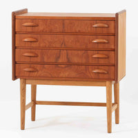 チーク材とオーク材を組み合わせた4段チェストです。前板には美しい木目を持つチーク材、脚部には明るく堅牢なオーク材が用いられ、素材のコントラストが北欧らしい洗練された印象を与えます。緩やかな曲線を描く取手や、すっきりとしたプロポーションが全体を端正にまとめ、コンパクトな幅59cmながら十分な収納力を備えています。リビングや寝室、書斎などさまざまな空間に取り入れやすく、ビンテージならではの風合いと実用性を兼ね備えた一台です。